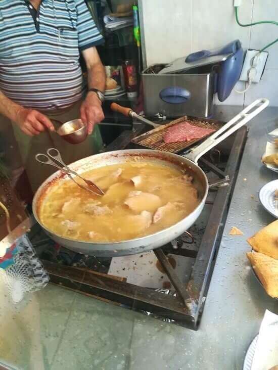 Preparazione di "bifana" a Lisbona: lonza di maiale cotta nello strutto
